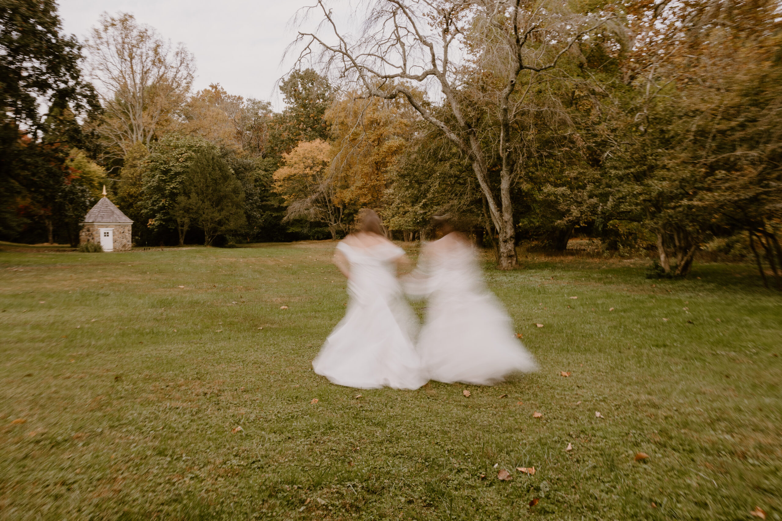 two brides running through a field in fall